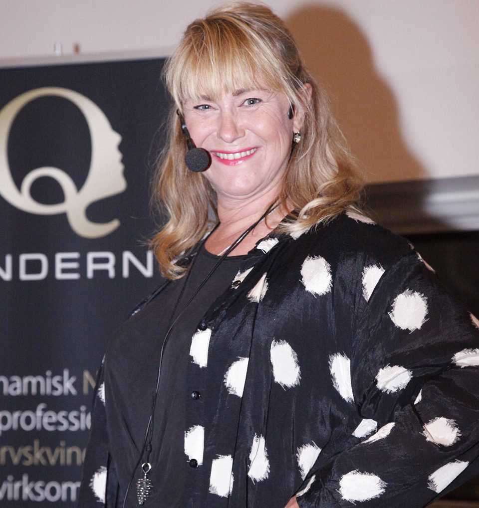 Foredragsholder på scenen foran Q-vindernes banner