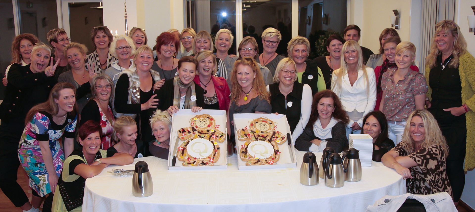 Q-vinderne samlet om middagsbordet med kager formet som Q